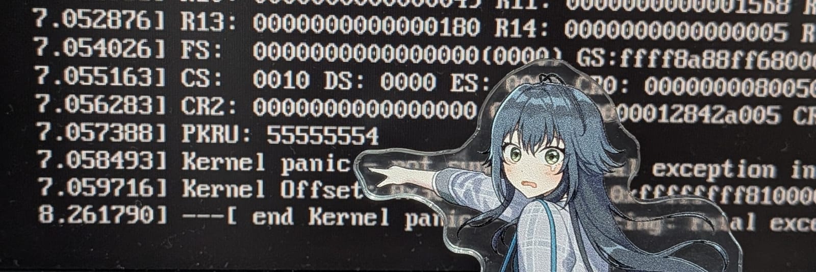 Foto de um monitor mostrando um kernel panic do Linux, com um boneco de acrílico apontando para o texto